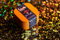 Orange Starlight Editions tin on a glittery background