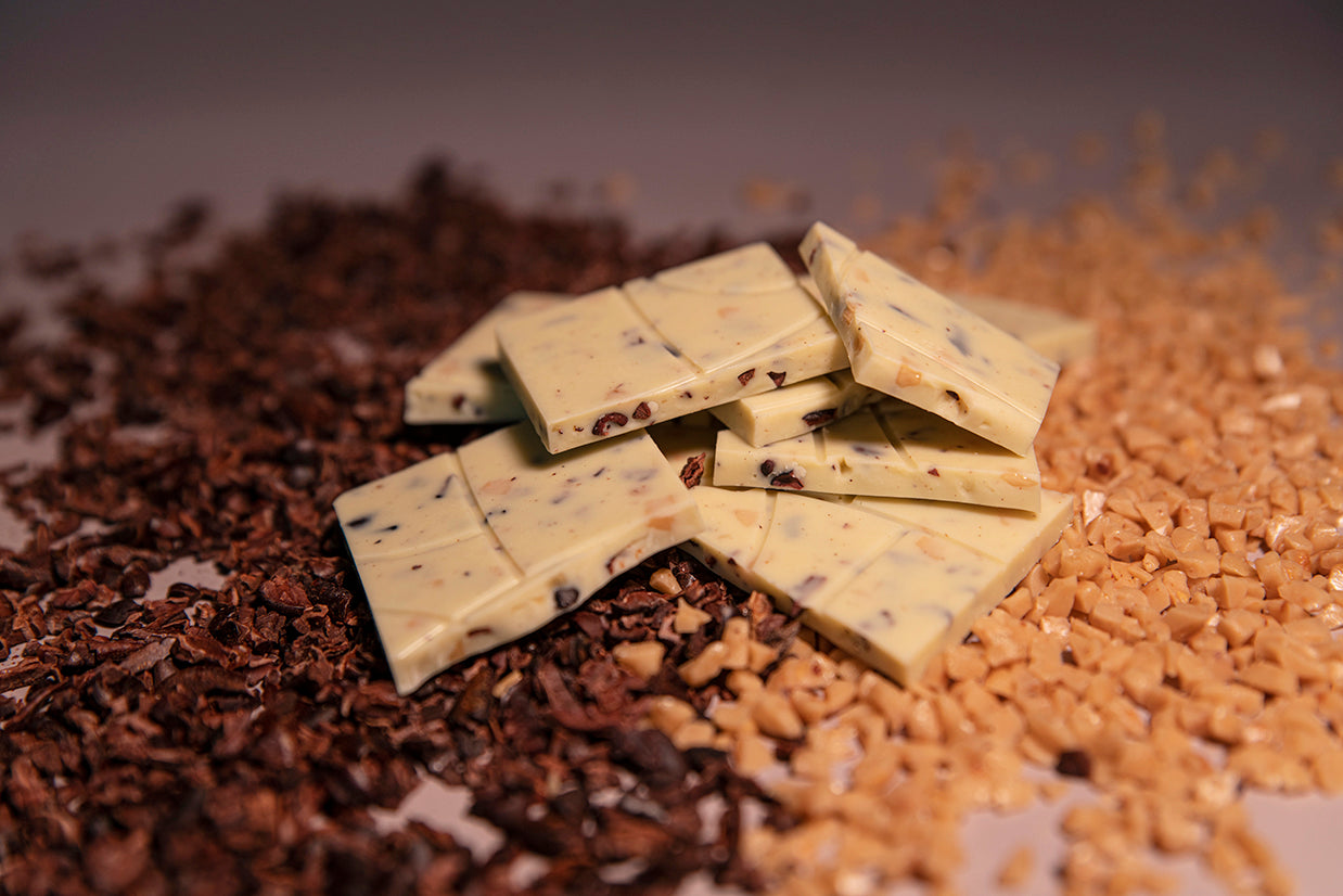 Mauna Kea Snow bar split into pieces separating piles of cocoa nibs and cruched toffee